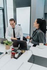 Two professionals in an office share a friendly discussion over laptops, notes, and a cup of coffee. A collaborative, diverse team atmosphere highlights teamwork, planning, and business communication.