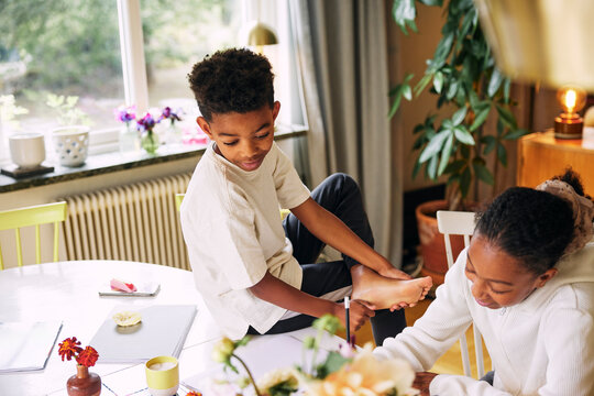 High angle view of boy looking at sister doing homework in home