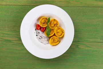 Ravioli on a plate. On a green background.