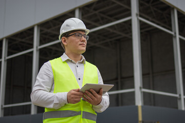 Engineer in a white hard hat. Tablet.. High quality photo