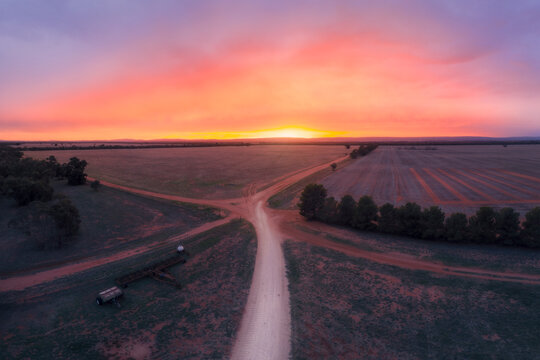 Aerial view of a road junction through remote rural farmland at sunrise, Australia