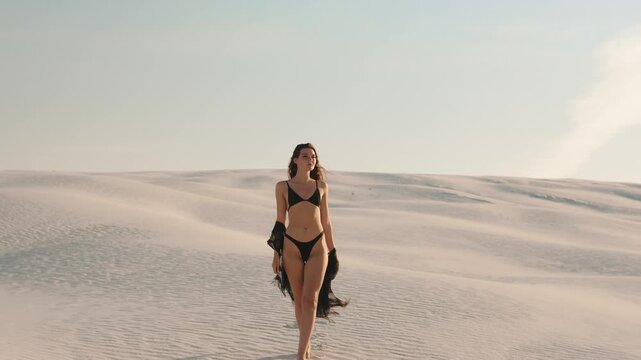 Stylish Bikini-Clad Woman Walking Straight Across Sunlit Desert