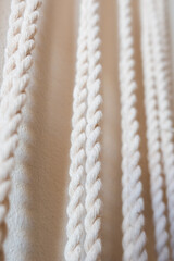 Close-up of a handmade macrame wall hanging. The intricate knots and patterns are visible, showcasing the craftsmanship and texture of the natural fibers.
