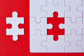 white Jigsaw puzzle with missing piece on red background