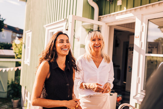 Happy mother and daughter enjoying leisure time while standing on villa porch