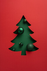 A minimalist green Christmas tree with glossy ornaments against a bold red backdrop creates a festive holiday scene. Ideal for Christmas, New Year greetings, and seasonal gift campaigns