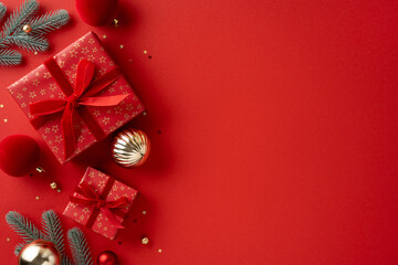 Vibrant Christmas scene with red gifts, gold ornaments, and pine branches on a red backdrop, ideal for holiday greetings and festive celebration themes
