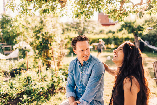 Happy woman enjoying leisure time with male friend at garden party