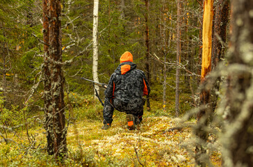 Hunter with his hunting rifle outdoor in the autumn wilderness hunting moose