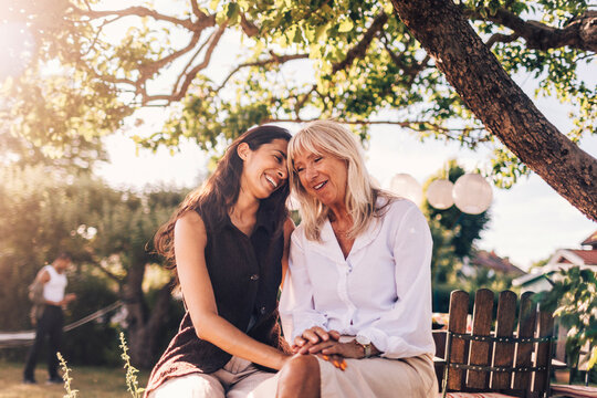 Affectionate smiling woman spending leisure time with mother at garden party