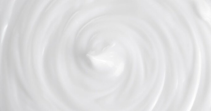 Cosmetic cream on a rotating table. Macro white smooth face cream texture, abstract beauty cosmetics background.