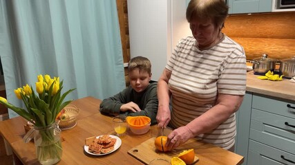 Capturing a timeless kitchen activity, this video shows an elderly woman and a young boy happily making fresh-squeezed orange juice for their family breakfast. - Powered by Adobe