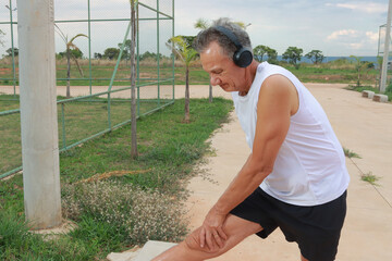 Older Man stretching his leg at an outdoor park before exercising 