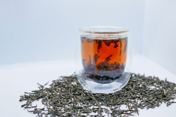 Glass Cup of Black Tea and Loose Leaves on White Background