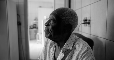One Elderly Afro-descendant man in black and white profile view, gazing upward with a thoughtful and calm expression, seated in a quiet indoor home setting