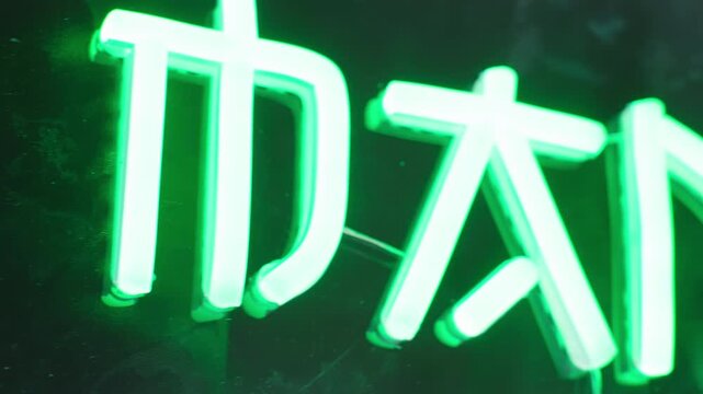 Dolly slide over glowing green Manga word on neon text sign close-up 4K