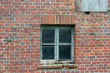 Old brick wall with a weathered window showcasing rustic charm in a rural setting