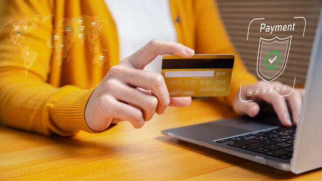 Woman using credit card for secure online payment on laptop. Concept of e-commerce, fintech, digital banking, cybersecurity, and global cashless transaction.