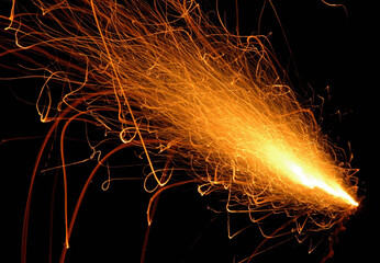 Dynamic fiery orange sparkler trails captured in motion against a black background, symbolizing...