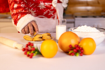 Santa's hand is reaching for a freshly baked cookie, surrounded by ingredients 
