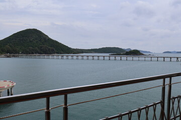 Obraz premium A serene waterside setting with a vast body of water stretching out to the horizon. A pier extends into the water from the foreground, offering a view of a boat dock