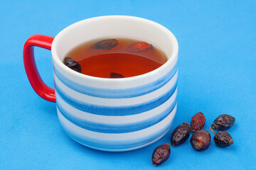 A cup of rosehip tea with rosy berries. Rosehips are rich in vitamin C and are beneficial for the immune system, the cardiovascular system, and help with colds.