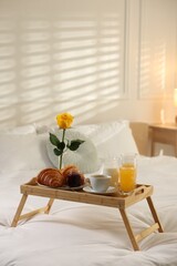Tray with delicious breakfast on bed in hotel room. Space for text