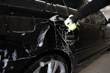 Man washing auto with sponge at car wash, closeup