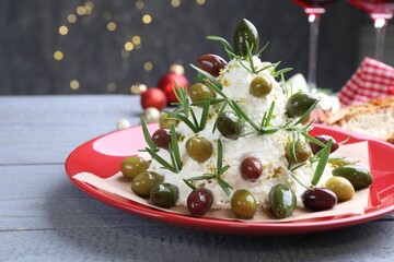 Delicious Christmas tree cheese ball with olives and rosemary on wooden table against grey background with blurred lights, closeup. New Year's appetizer