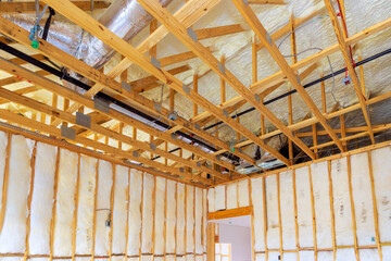 Wooden frame structure insulation materials are indicating ongoing construction work in new home.
