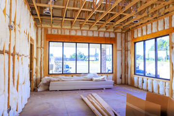 Fototapeta premium Inside building under construction exposed framing, insulation, unfinished floors, tools, materials.
