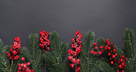 Flat lay composition with fir tree branches and Christmas decor on black background. Space for text