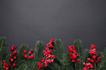 Flat lay composition with fir tree branches and Christmas decor on black background. Space for text