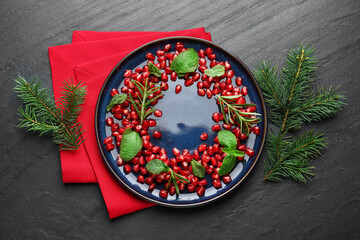 Christmas food. Pomegranate seeds, mint, rosemary and fir tree branches on dark textured table, flat lay