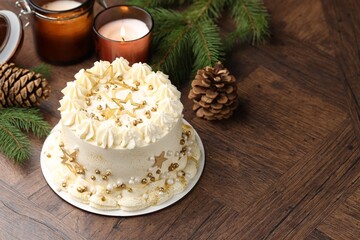 Delicious cake with Christmas decor and burning candles on wooden table. Space for text