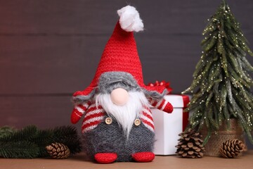Naklejka premium Funny Christmas gnome and festive decor on wooden table