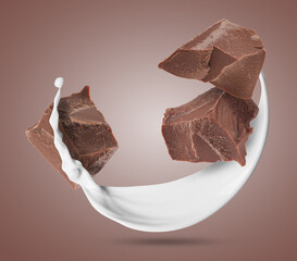 Milkshake splash and chocolate pieces in air on brown background