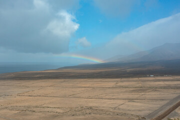 Dirt Road Through the Plains of Fuerteventura with a Rainbow Over the Coast