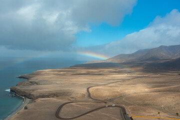 Dirt Road Through the Plains of Fuerteventura with a Rainbow Over the Coast