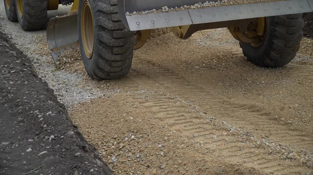 Earth movers leveling ground on road construction in field.
 A bulldozer moves the ground with an attached blade on a worksite.
Bulldozers level the sand at the landfill.
