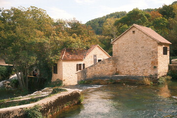 Traditional stone watermills on a flowing river with terracotta roofs