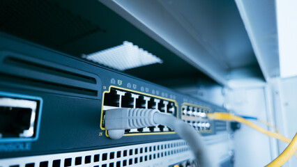 Gray ethernet cable connected to professional switch in server cabinet, symbolizing network management, cybersecurity, and stable digital data infrastructure