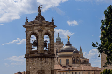 Horizontal panorama reveals harmony of Bergamo towers and domes, where cathedral bells, golden archangel, and medieval spires form elegant skyline