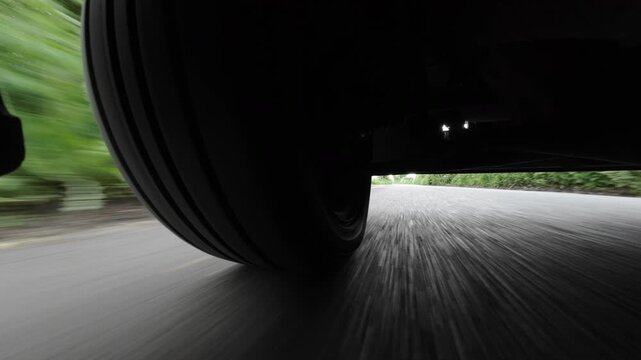Low-mounted action-camera view beneath a car speeding along a bright country road near Sevenoaks, Kent, United Kingdom, turning several corners through open countryside.