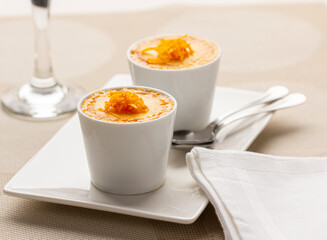 Homemade orange custard puddings on a white plate, garnished with orange zest.
