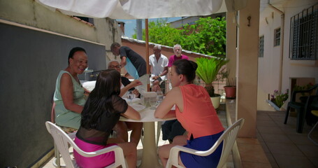 Family bonding during lunch outdoors, multigenerational relatives sharing food, conversation, and laughter, fostering connection in a casual patio setting