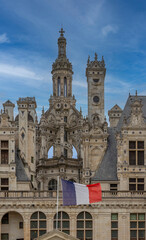 Fototapeta premium Chambord, France - 10 27 2025: Detail view of the Chambord Castle roof with balconies, tower of the double helix staircase and french flag