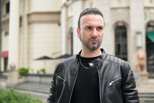 Fototapeta Handsome bearded man in black leather jacket posing in city streets