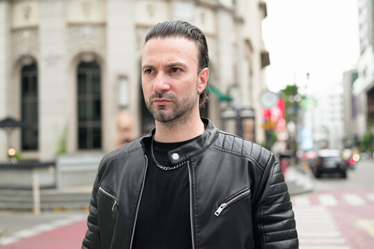 Fototapeta Handsome bearded man in black leather jacket posing in city streets