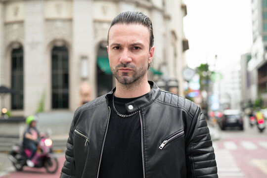 Fototapeta Handsome bearded man in black leather jacket posing in city streets